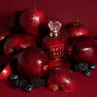 Frasco de perfume vermelho KAY ALI entre maçãs e frutos vermelhos