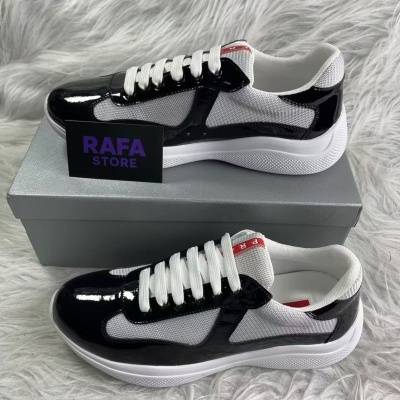 Sapatilhas desportivas preta, branca e cinza sobre caixa cinza em tapete felpudo.