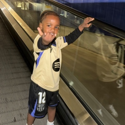 Criança com roupa desportiva amarela, preta e azul e sapatilhas Adidas num tapete rolante.