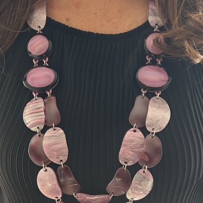 Fabuloso Colar em Resina Lilás Colar feminino em tons de rosa e lilás sobre blusa preta plissada