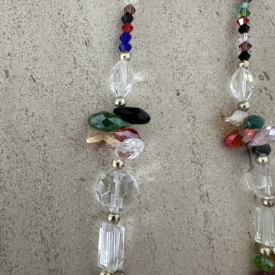 Colares de contas de vidro coloridas e transparentes sobre superfície cinza