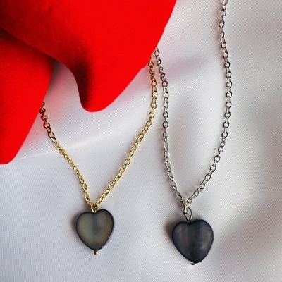 Colares com pendentes de coração e correntes dourada e prateada sobre tecido branco