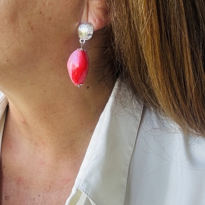 Brinco prateado com pendente de pedra vermelha brilhante numa orelha feminina