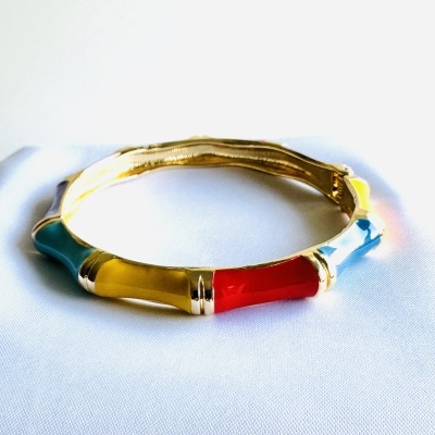 Pulseira rígida dourada com segmentos coloridos em azul, amarelo, vermelho e azul claro