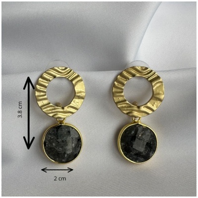 Brincos dourados com pendente preto sobre tecido branco