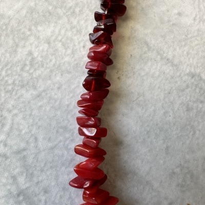 Colar de pedras vermelhas irregulares sobre tecido cinzento