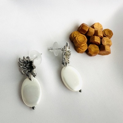 Par de brincos metálicos prateados com pendente oval branco e pequenos blocos de madeira hexagonais