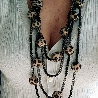 colar com contas padrão leopardo e correntes metálicas sobre camisola branca de malha