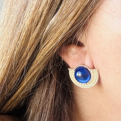 Brinco ear cuff dourado com pedra azul na orelha de mulher com cabelo castanho claro