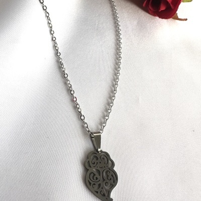 Colar prateado com pendente decorativo e rosa vermelha ao lado