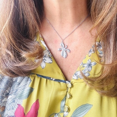 Colar prateado com pendente de folha e vestido floral amarelo