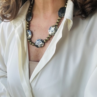 Colar com contas ovais marmoreadas azuis e brancas e contas esféricas douradas, vestido com camisa branca