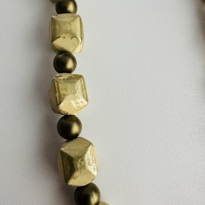 Colar com contas douradas facetadas e esferas bronze escuro sobre fundo branco