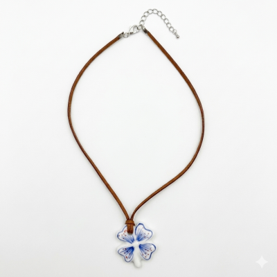 Colar com pendente de porcelana branca com padrão azul e castanho e cordão castanho.