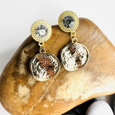 Brincos dourados com pedra transparente central sobre pedra castanha