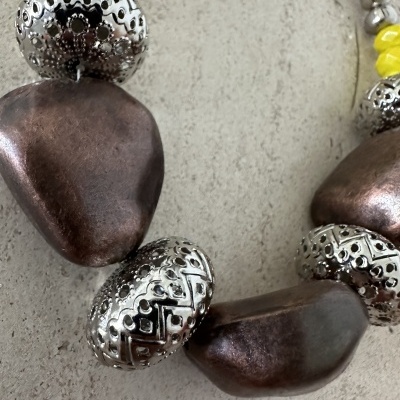 Colar com contas grandes de metal prateado e pedras castanho escuras com pequenas contas amarelas