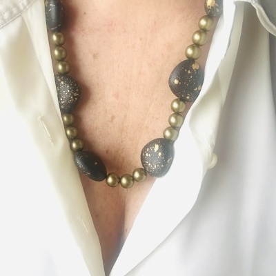 Colar com pedras pretas e bolas douradas usada com camisa branca