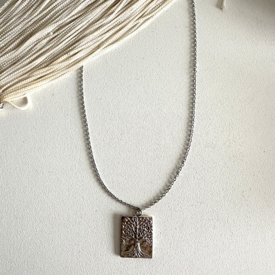 Colar prateado com pendente de árvore em relevo sobre fundo branco