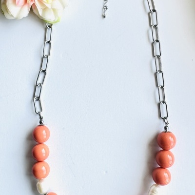 Colar com contas rosa alaranjado e pérolas em fundo branco com flor decorativa