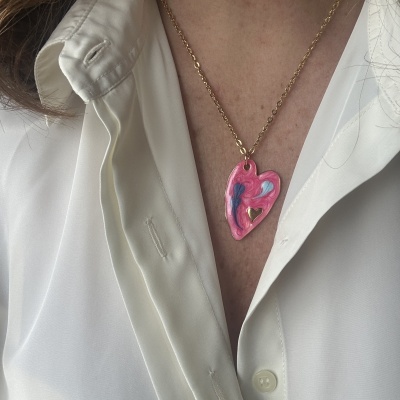 Colar dourado com pendente em forma de coração rosa com detalhes em azul e branco