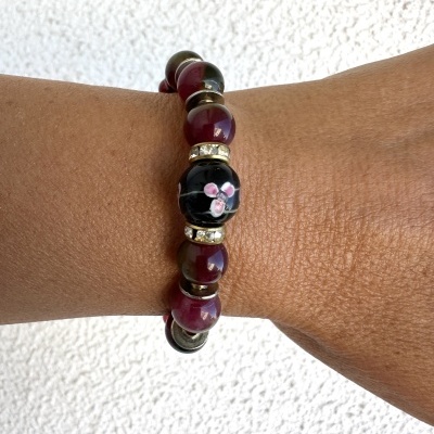 Pulseira colorida com contas esféricas e flor desenhada no pulso