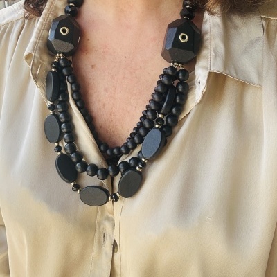 Colar preto com contas de vários tamanhos e formas em camisa bege clara