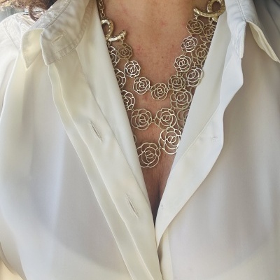 Colar de metal prateado com design de flores usado com camisa branca