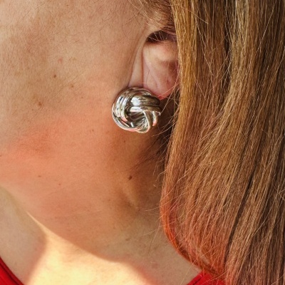 Brinco prateado em formato de nó num ouvido feminino