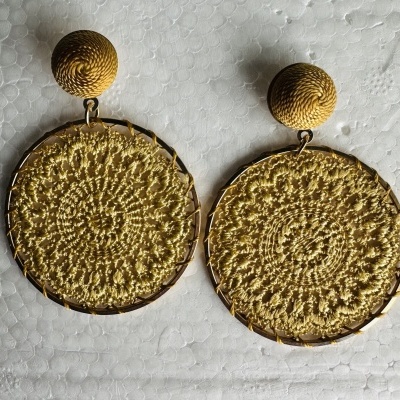 Brincos dourados com padrão de crochê amarelo claro em fundo branco