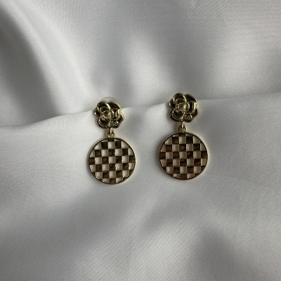 Brincos dourados com pendente circular xadrez em fundo branco