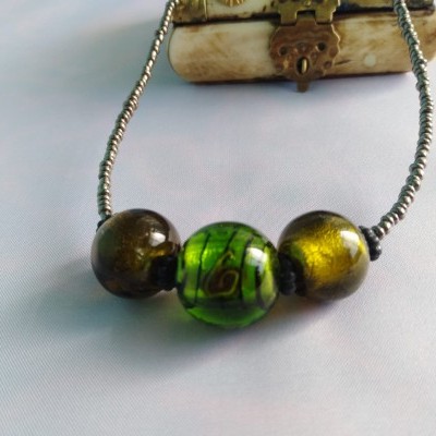 Colar com contas grandes castanhas e verde sobre tecido branco