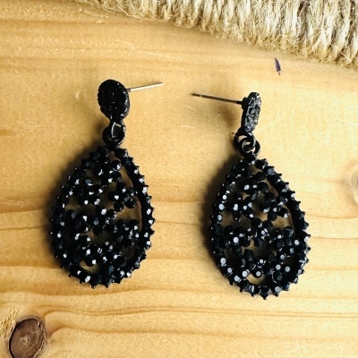 Brincos pretos em forma de gota com relevo sobre madeira clara