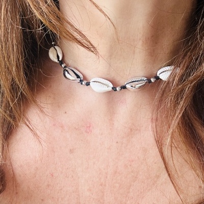 Colar de conchas brancas e castanhas com nós negros ao pescoço