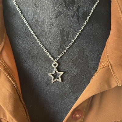 Colar prateado com pendente em forma de estrela num manequim com vestido castanho