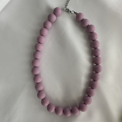 Colar de contas rosa mate com fecho metálico sobre tecido branco