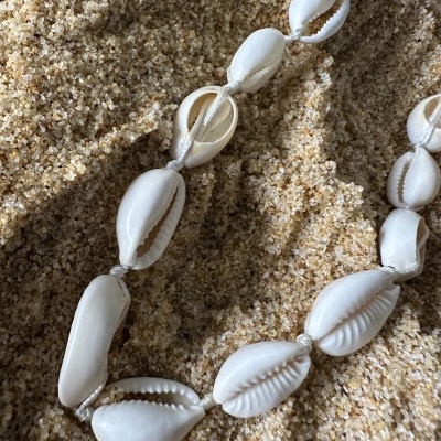Colar de conchas brancas em areia clara