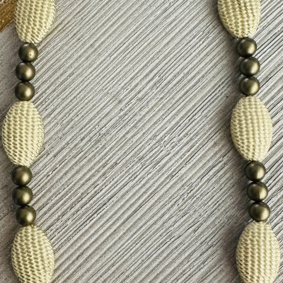 Colar com contas ovais bege e contas metálicas bronze sobre tecido listrado bege e castanho