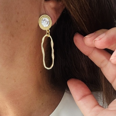 Brinco dourado com pedra transparente e pendente oval em orelha