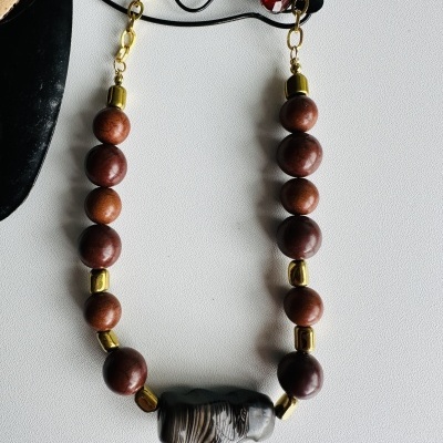 Colar com contas de madeira, contas douradas e peça central preta com padrão branco
