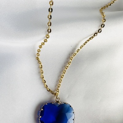 Colar dourado com pendente em coração azul escuro sobre fundo branco