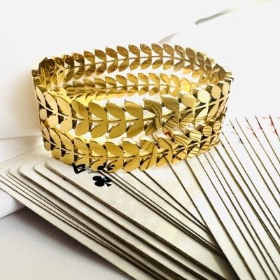 Pulseira dourada em padrão de folhas sobre cartas de baralho
