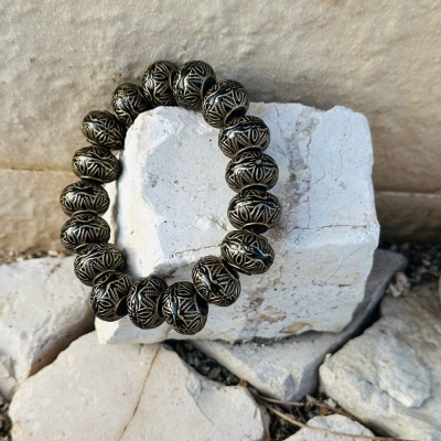 Pulseira de contas metálicas gravadas em pedra branca.