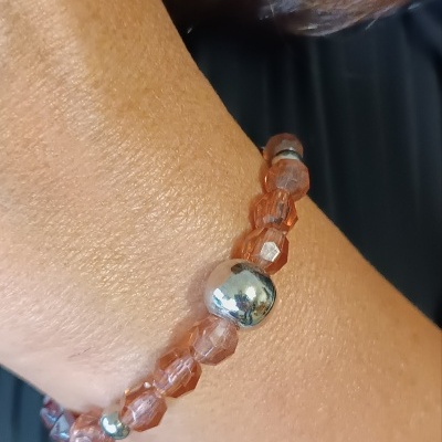 Pulseira elástica de contas âmbar e metálicas prateadas no pulso