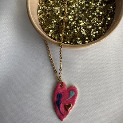 Colar com pendente em forma de coração colorido e estrela dourada em tigela.