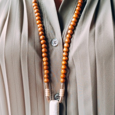 Colar de contas de madeira castanha com pendente branco em camisa verde claro
