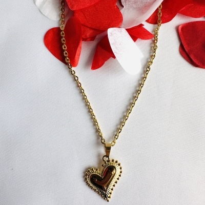 Colar dourado com pendente de coração e decoração de corações em papel vermelho e branco.