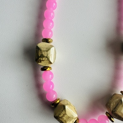 Colar com contas rosas fluorescentes e contas metálicas douradas.