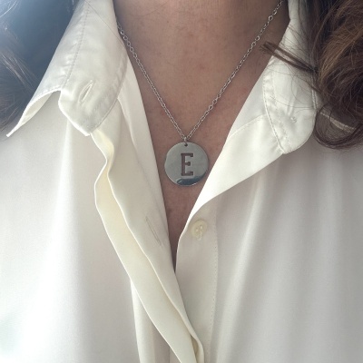 Colar prata com pendente letra E em camisa branca