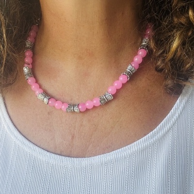 Colar de contas rosa e prateadas usado no pescoço