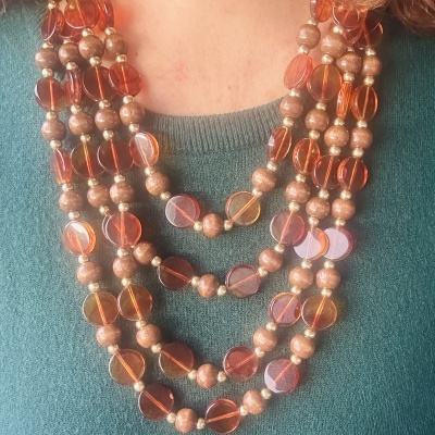 Colar multi-voltas com contas âmbar e bronze sobre suéter verde-escuro